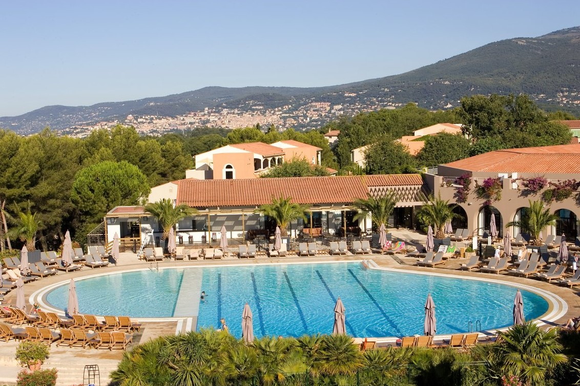 Aerial view of the pool at Club Med Opio in Provence with the resort complex in the background and the city in the distance. Aerial view of the pool at Club Med Opio in Provence with the resort complex in the background and the city in the distance.