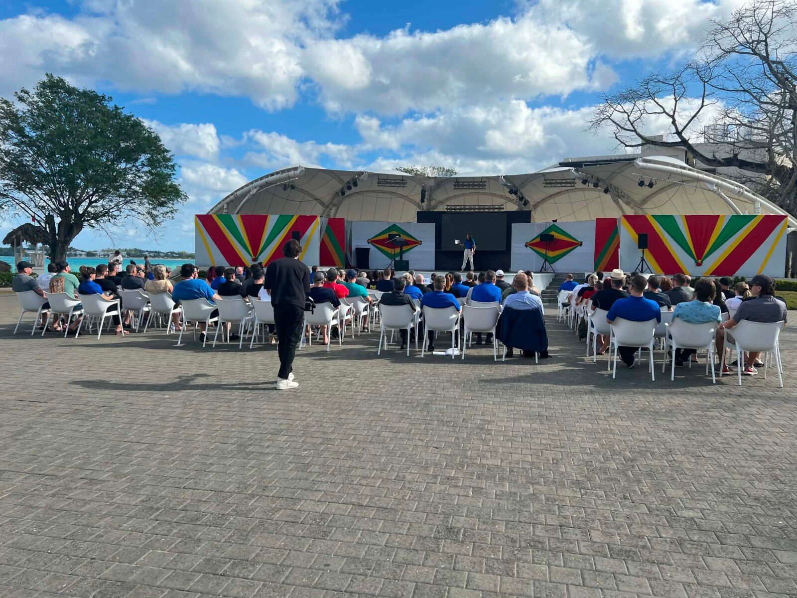 Participants assis face à la scène pendant une présentation de congrès en plein air