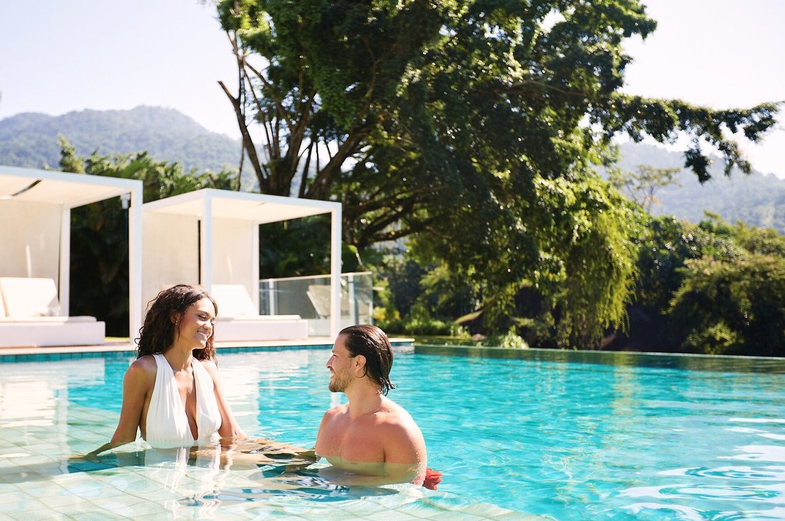 Couple relaxing in the pool at Club Med Rio Das Pedras with daybeds under pergolas in the background. Couple relaxing in the pool at Club Med Rio Das Pedras with daybeds under pergolas in the background.