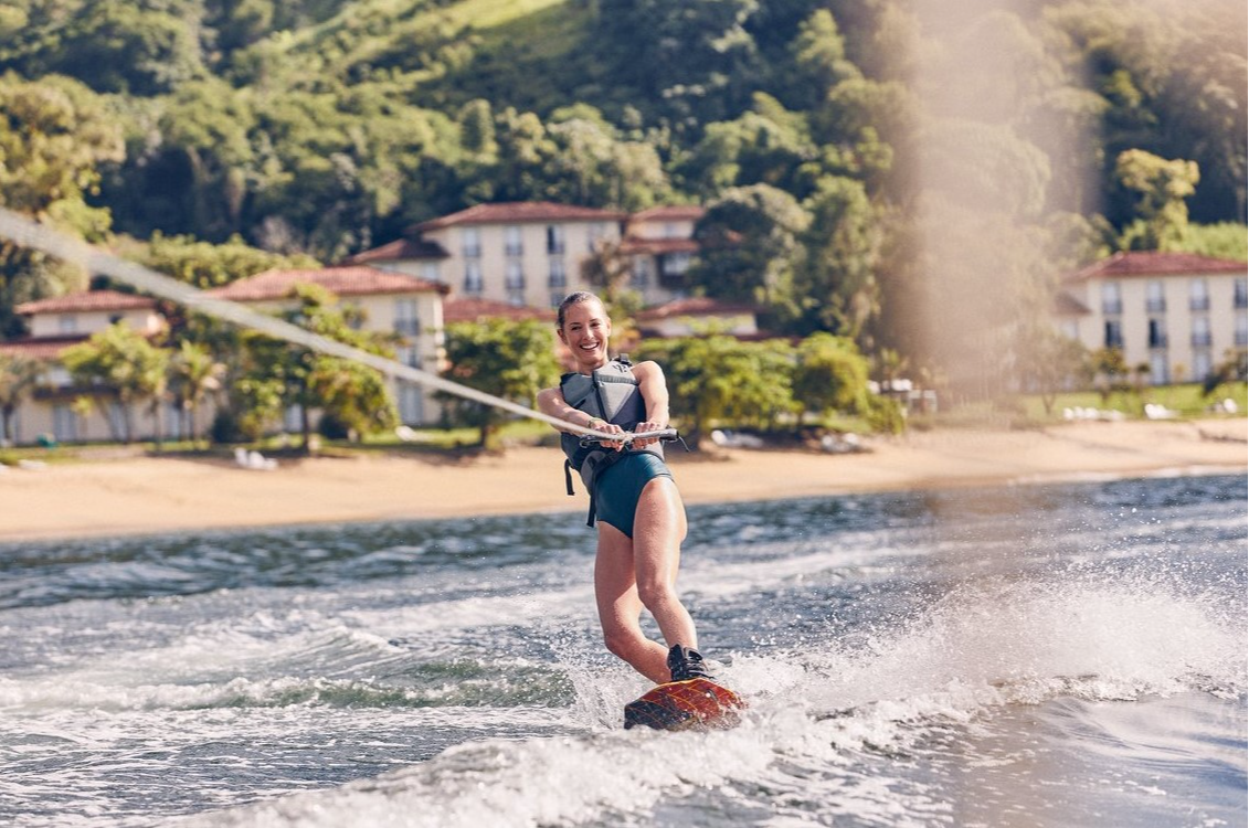 Front view of a woman wakeboarding on the emerald blue waves of the Atlantic at Club Med Rio Das Pedras. Front view of a woman wakeboarding on the emerald blue waves of the Atlantic at Club Med Rio Das Pedras.