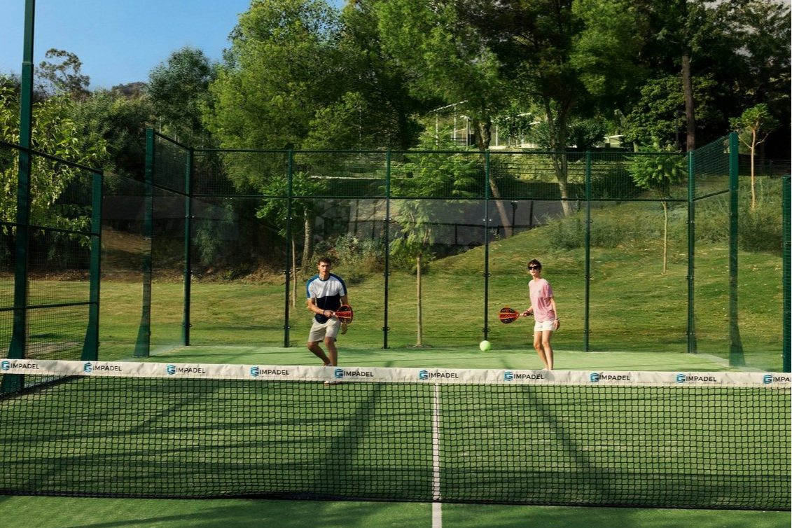 Couple jouant au padel en équipe sur un terrain synthétique entouré de parois vitrées au Club Med Opio en Provence. Couple jouant au padel en équipe sur un terrain synthétique entouré de parois vitrées au Club Med Opio en Provence.